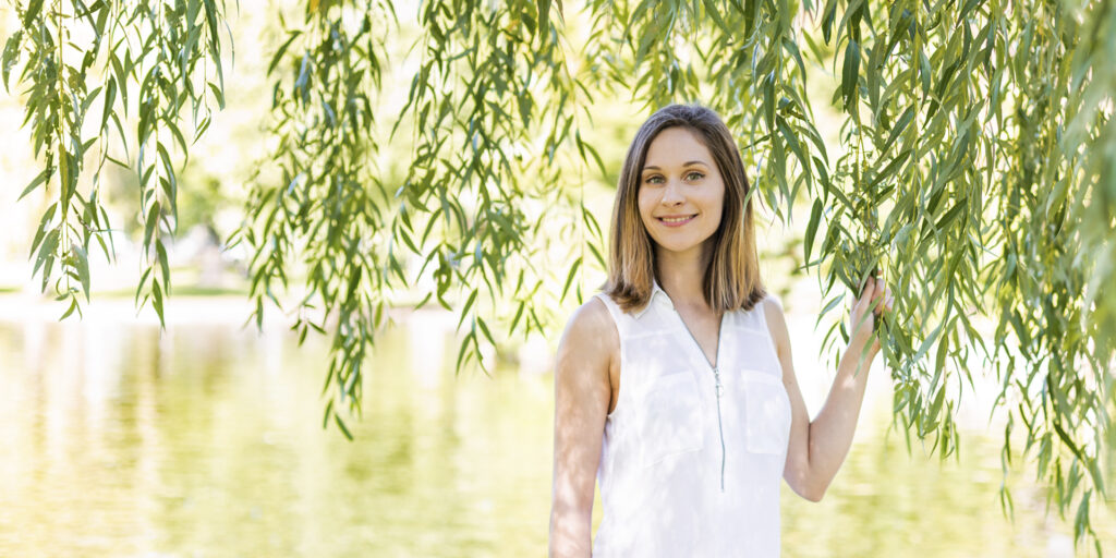 Dr. Kara Larson standing under a willow tree beside water